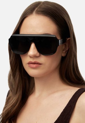 Black oversized sunglasses with a sleek frame, glossy finish, and dark lenses. Metal accents on the temples add detail to the design.