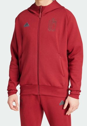 Sweatshirt rouge zippé avec capuche, arborant un logo sur la poitrine gauche et des accents gris. Fabriqué en tissu texturé avec une coupe décontractée.