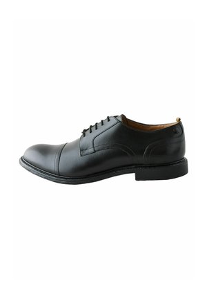 Zapato de dress de cuero negro con punta redondeada, diseño de cordones, acentos cosidos y un tacón ligeramente elevado. Textura suave y hardware minimalista.
