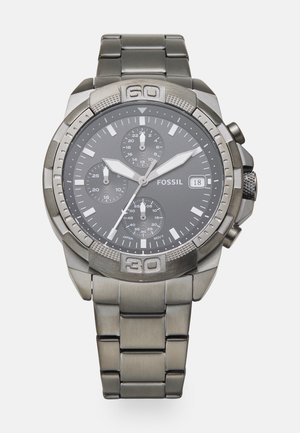 Orologio cronografo con bracciale in metallo grigio e quadrante grigio scuro. Caratteristiche includono tre sottodial, dettagli in argento e una lunetta prominente.