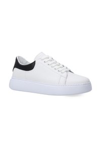 Weiße Leder-Sneaker mit einem schwarzen Fersenbereich, runder Zehenpartie, flacher, weißer Sohle und weißen Schnürsenkeln. Glatte Textur und einfaches Design.