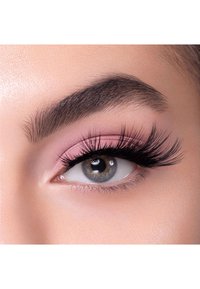 Gros plan sur un œil avec de longs cils noirs, un fard à paupières rose clair et un teint légèrement rosé, avec un iris gris rond.