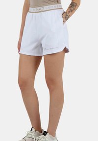 Vita sportshorts med en beige elastisk midja som har "EA7 EMPORIO ARMANI" logotyp, sidofickor och en lös passform.
