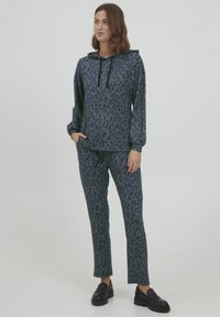 Tuta blu con stampa leopardata realizzato in tessuto morbido, composto da una felpa con cappuccio e lacci e polsini elastici, abbinato a pantaloni dritti.