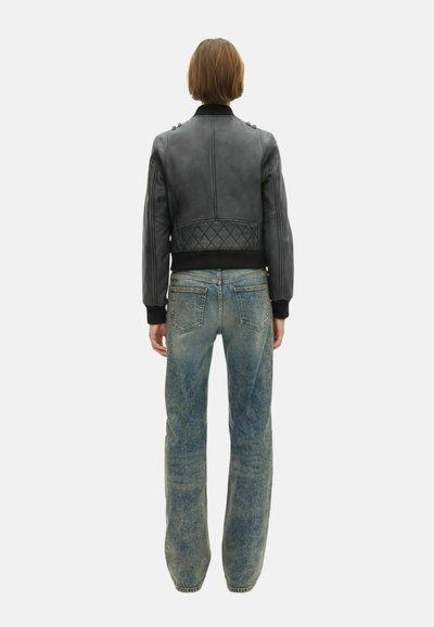 Zwarte leren bomjacket met een gevoerd achterpaneel en geribbelde manchetten, gecombineerd met vervaagde blauwe straight-leg jeans met een versleten structuur.