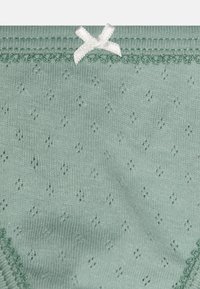 Slip in cotone verde menta con un delicato motivo di piccoli diamanti, orlo a scallop e un accento di fiocco bianco in vita.