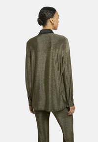 Olijfgroen overhemd met lange mouwen in een glanzende, metallic stof, met een zwarte kraag en knoopmanchetten, voorzien van een losse, relaxte pasvorm.