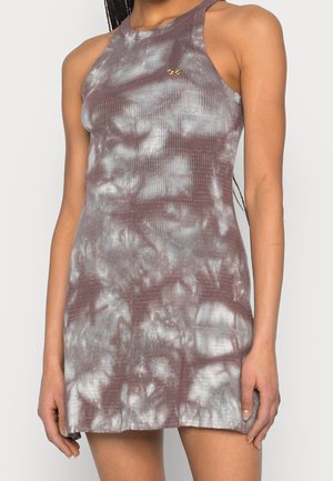 Robe sans manches, moulante, à effet tie-dye violet et blanc, avec un petit emblème doré sur la poitrine, portée par une personne aux cheveux tressés.