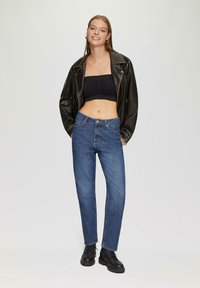 Zwarte leren jas, cropped zwart topje en blauwe jeans. De denim heeft een rechte pasvorm, 5-pocket design en een subtiel vervaagd patroon. Zwarte laarzen.