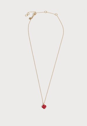 Delicado collar de cadena de oro con un pequeño colgante rojo de trébol de cuatro hojas y cierre ajustable con dos pequeños charms redondos.