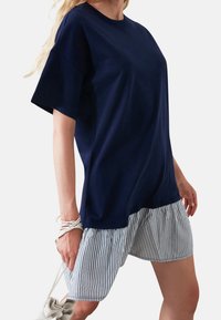 Navyblaue T-Shirt mit kurzen Ärmeln, kombiniert mit gestreiften Stoffshorts. Hat einen lässigen Schnitt und einen geraden Saum.