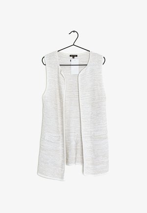 Gilet léger texturé sans manches en blanc cassé avec deux poches avant et un design ouvert à l'avant. Accroché à un crochet noir.