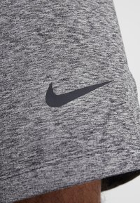 Bermudas deportivas grises fabricadas con tela texturizada, que cuentan con un logotipo negro de Nike en el lado inferior. Diseño suave y liviano.