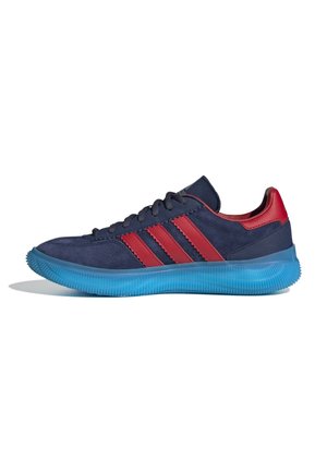 Marineblaue Sneaker mit roten Streifen und Ferse, schwarzen Schnürsenkeln und einer durchsichtigen, hellblauen Sohle, seitlich auf weißem Hintergrund dargestellt.