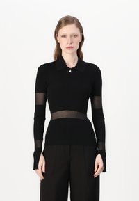 Top lungo a maniche nere a coste con colletto, caratterizzato da inserti trasparenti sulle maniche e in vita, impreziosito da una piccola embellissement.