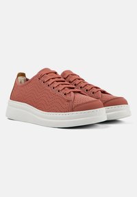Zapatillas de cuero perforado rosa con suelas de goma blanca, que presentan cordones redondos y un sutil patrón ondulado en la parte superior.