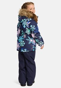 Marinblå vinterjacka med färgglada blommönster och fuskpälsluva, matchad med mörka byxor och svarta stövlar. Slät, vattentät material.