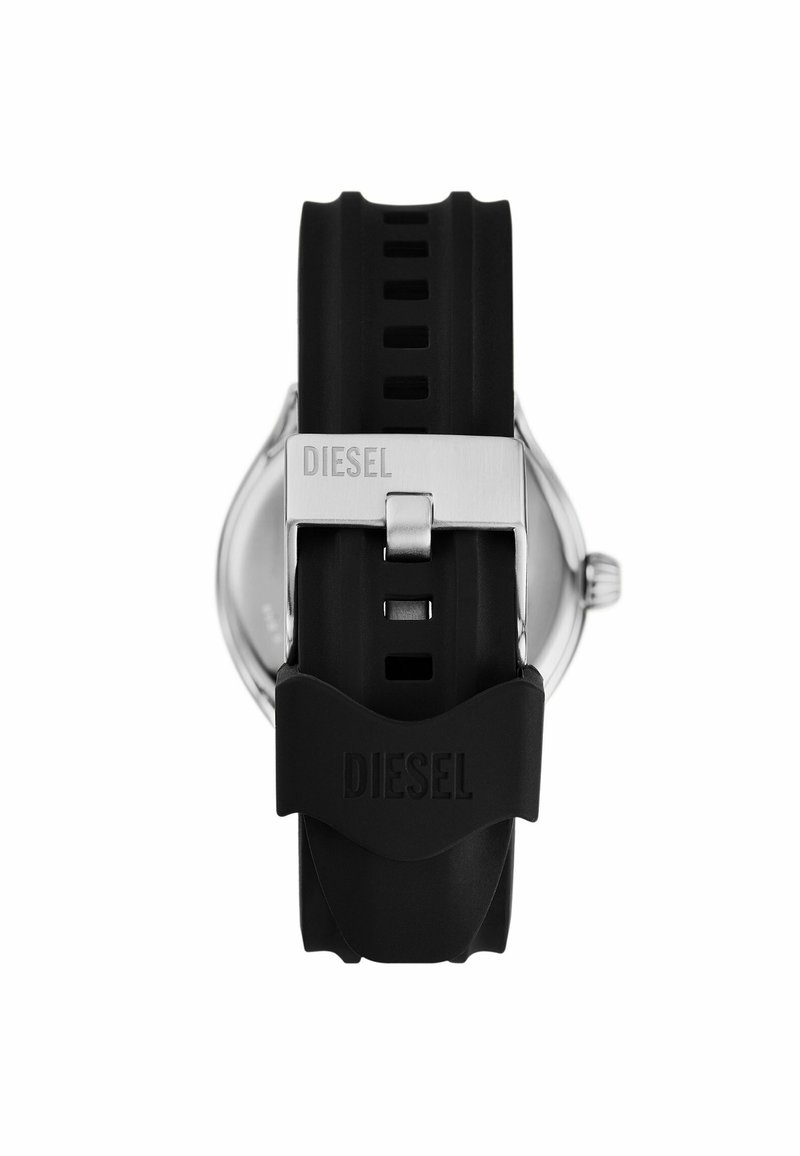 Correa de reloj de silicona negra con un hebilla de metal plateada grabada con "DIESEL". Carátula del reloj redonda parcialmente visible en el fondo.