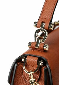 Borsa a mano in pelle marrone con finitura testurizzata, dettagli in metallo dorato e forma strutturata. Chiusura a doppio anello e dettagli con rifiniture nere.