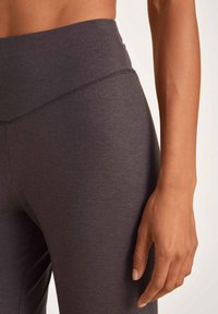 Graue Leggings mit glattem, dehnbarem Material und hoher Taille, featuring einen schlichten Bund und eine enganliegende Passform.