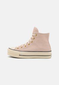 Höga sneakers i ljusrosa mocka med guldöglor, en beige gummisula och svart kant runt sulan. Klassisk tåhuvudsdesign.