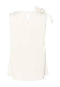 Blouse blanche sans manches avec un petit décolleté en keyhole et un nœud noué sur une épaule, sur fond blanc.