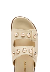 Sandalo scivoloso beige con due ampie cinghie decorate da chiodini metallici circolari, una parte superiore liscia e una soletta imbottita.