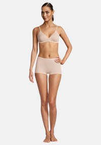 Jasnobeżowy zestaw braletki i szortów wykonany z gładkiego materiału, z cienkimi ramiączkami i bezszwowym wykończeniem.