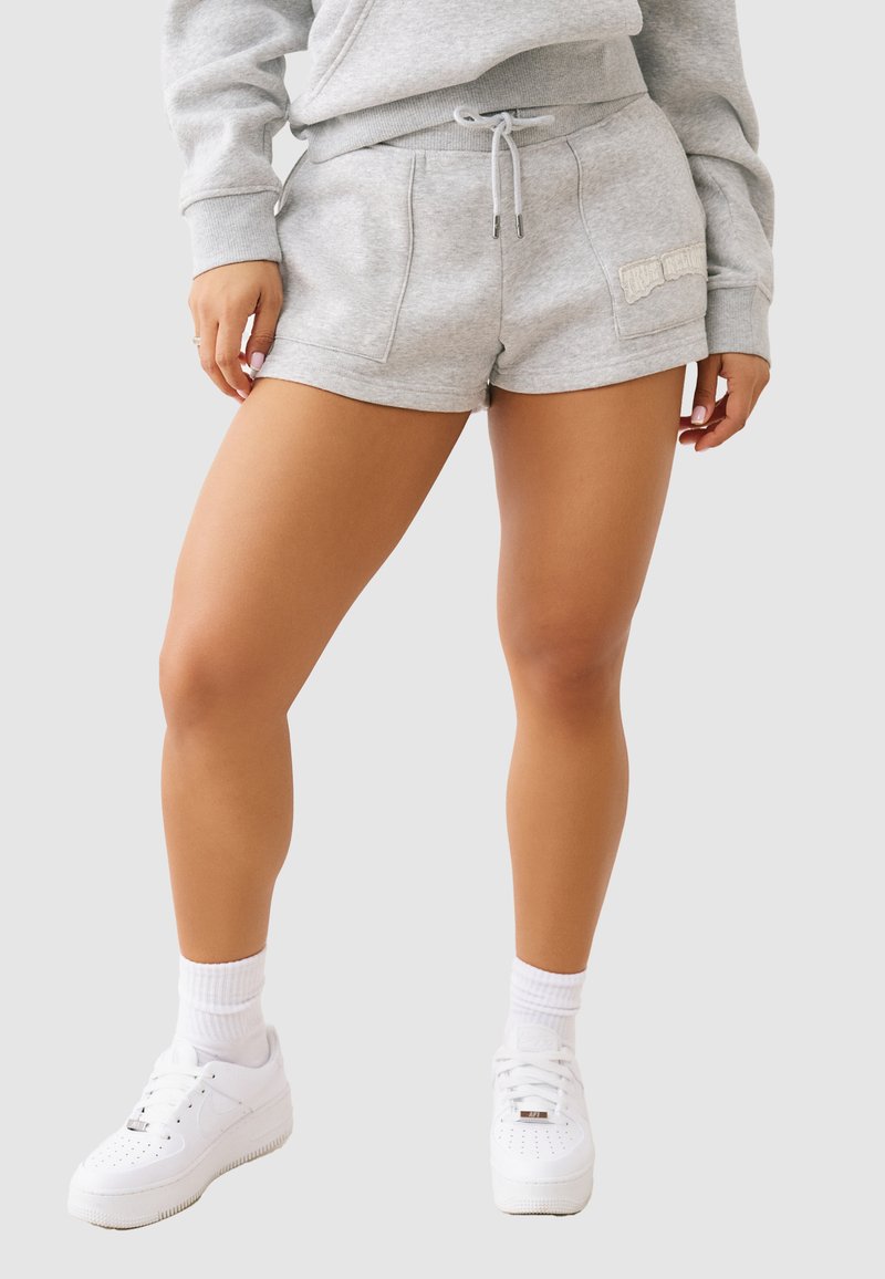 Szare bawełniane szorty z elastyczną talią, sznurkiem i bocznymi kieszeniami. Połączone z białymi trampkami i prążkowanymi białymi skarpetkami.