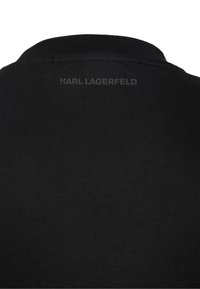 Svart bomullspiké med flat krage. Har en texturerad logotyp "KARL LAGERFELD" tryckt på baksidan. Slät tyg med klassisk passform.