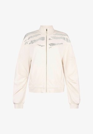 Jachetă albă cu fermoar, guler înalt, mâneci lungi, manșete tricotate și modele orizontale cu nituri argintii pe partea superioară a pieptului și umerilor.