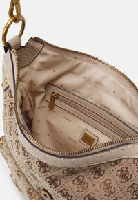 Borsa Guess beige con motivo monogram, cerniera dorata e tasca interna con zip che presenta ripetuti loghi "GUESS" sulla fodera in tessuto.