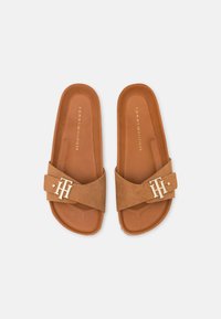 Sandales à glissière en daim marron avec une large sangle, ornées d'un accent logo métallique et d'une semelle intérieure lisse couleur caramel. Forme arrondie avec une semelle plate.