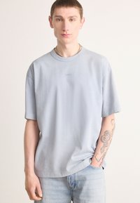 Lyseblå kortærmet t-shirt med rund hals, prydet med et broderet logo på brystet og en afslappet pasform.