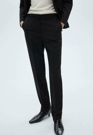 Black tailored trousers with a straight cut, featuring a smooth texture, belt loops, and side pockets, paired with pointed black shoes.