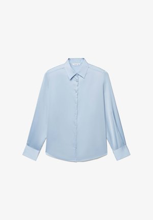 Camicia azzurro chiaro a maniche lunghe con bottoni, colletto appuntito e polsini larghi, distesa su uno sfondo bianco.