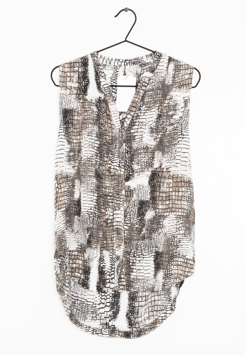 Blouse sans manches avec imprimé abstrait de reptile noir, blanc et beige, suspendue sur un cintre fin noir sur fond blanc.