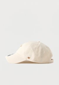 Casquette en coton beige avec une visière courbée, logo brodé en or, sangle réglable à l'arrière et trous de ventilation sur la couronne.