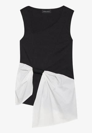 Svart ribbet ermeløs topp med asymmetrisk design, med en hvit tvunnet stoffdetalj i midjen og en rund utringning.