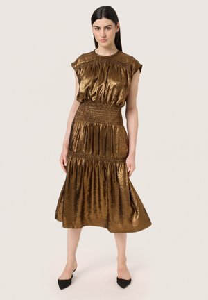 Bronzen metalen midi-jurk met korte mouwen, gerimpelde taille en gelaagde rok; gladde textuur met reflecterende glans; gecombineerd met zwarte hakken.