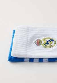 Hvide og blå fodboldsokker med ribbet tekstur og et logo-patch med en krone og gule bogstaver på den hvide sok.