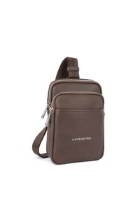 Borsa a tracolla in pelle marrone con finitura testurizzata, dotata di chiusura con zip, tasca frontale e dettaglio logo in metallo. Inclusa tracolla regolabile.