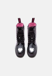 Μαύρα γυαλιστερά μποτάκια με κορδόνια και ροζ εσωτερικό, ασημί διακοσμήσεις καρδιές στα δάχτυλα και ροζ ραφές στις χοντρές σόλες, απεικονιζόμενα από πάνω.