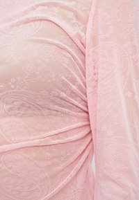 Ροζ διάφανο ύφασμα με λουλουδένιο μοτίβο και υφή με ανάγλυφη λεπτομέρεια. Διαθέτει σχεδιασμό με πιέτες και απαλή πτώση ύφους· ελαφρύ και λεπτεπίλεπτο στην όψη.