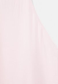 Tissu sans manches rose clair avec une texture lisse et une couture inclinée courant verticalement sur le côté droit.