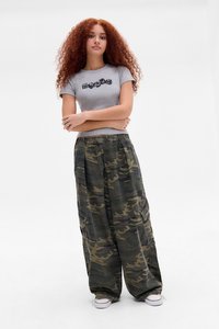 Grå t-shirt med korte ærmer og sort grafisk design, parret med løstsiddende grønne camo cargo-bukser og hvide sneakers.