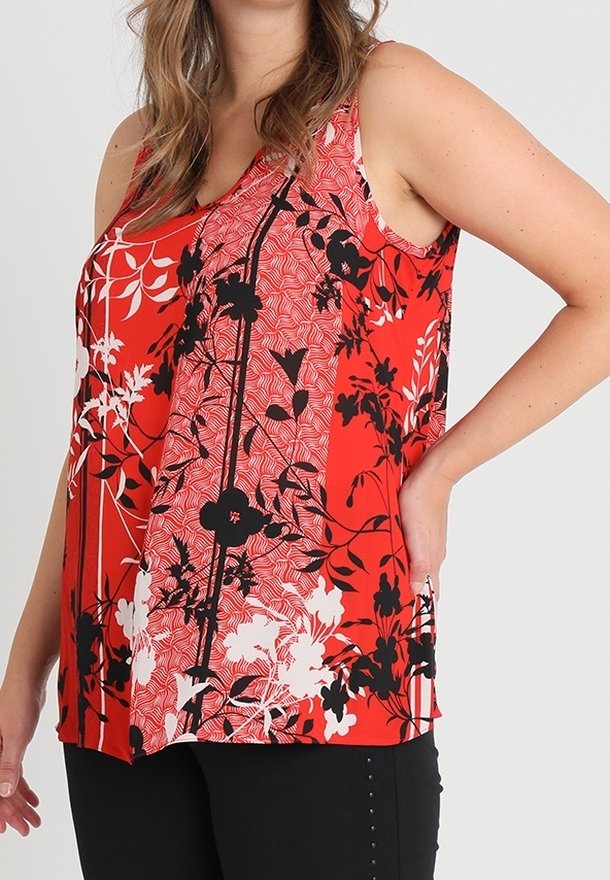 Rotes Blumen-Top mit schwarz-weißen Blumenmustern, mit lässigem Schnitt und schulterfreiem Design, kombiniert mit schwarzen Hosen.