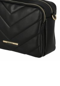 Borsa nera in ecopelle con motivo a chevron, doppie zip e una placca del marchio in tonalità oro sul davanti. Finitura testurizzata con un aspetto morbido.