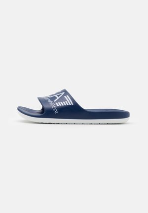 Sandale slide bleu marine avec semelle blanche, bout ouvert, et large bride présentant le logo blanc audacieux "Emporio Armani" et un symbole d'aigle.