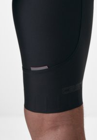 Schwarze Radsportshorts aus elastischem Material, mit einem strukturierten Grip-Band am Saum und einem dezenten Logo an der Seite.